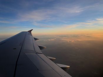 Airplane wing against sky during sunset