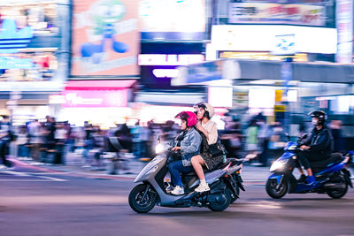 Side view of man riding motor scooter on street