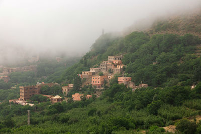 Houses amidst trees and buildings against sky