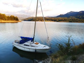 Sailboats moored in lake against sky