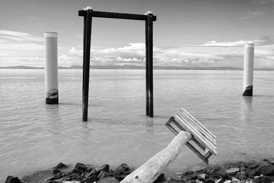 Wooden posts in sea against sky