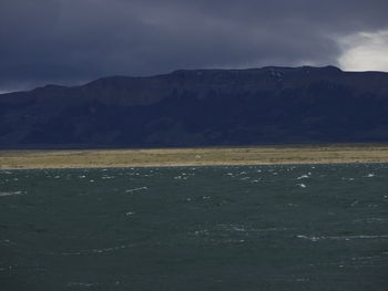 Scenic view of sea by mountains against sky