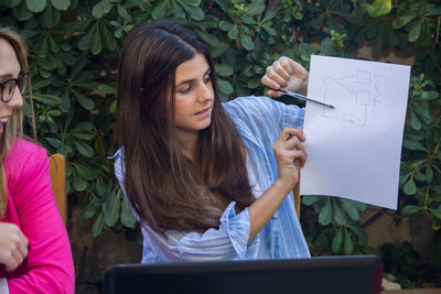 Young woman looking away while standing on paper