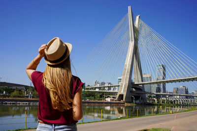 Back view of traveler girl enjoying sight of estaiada bridge in sao paulo, brazil.