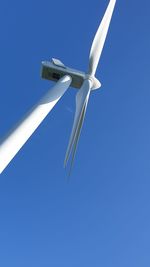 Low angle view of wind turbine against clear blue sky