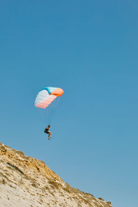 Young man paragliding during summer off cliffs in baja, mexico.