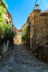 Walkway amidst buildings against sky