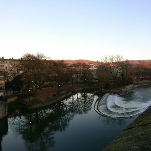 Reflection of trees in river against clear sky