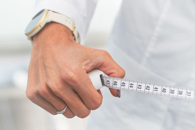 Midsection of man holding thermometer