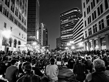 Crowd on city street amidst buildings at night