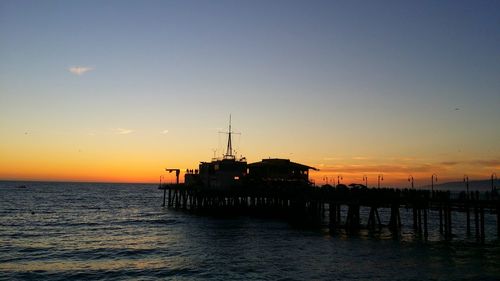 Silhouette ship in sea against sky during sunset