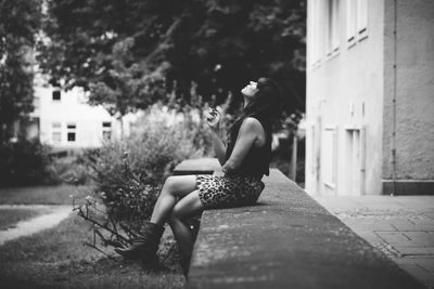 Full length of woman sitting on tree