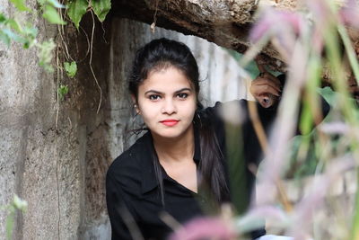 Portrait of young woman against tree trunk