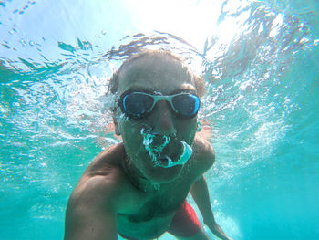 Portrait of shirtless man swimming in sea