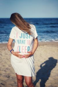 Rear view of woman holding umbrella at beach