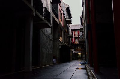 Empty narrow street amidst buildings at night