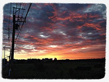 Scenic view of landscape against cloudy sky at sunset