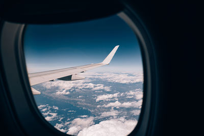 Airplane flying in sky seen through glass window