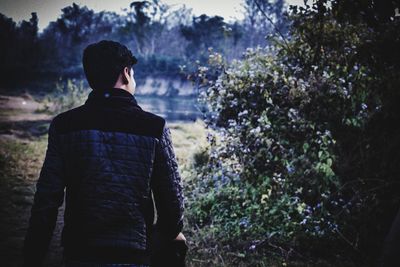 Rear view of man walking by plants