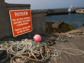 Ropes by warning sign at harbor