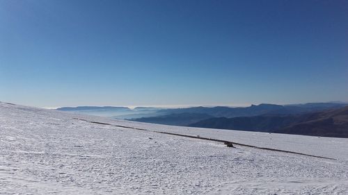 Scenic view of snowcapped mountains against clear blue sky