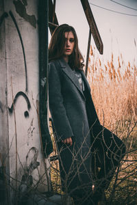 Portrait of young woman standing by old wall