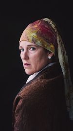 Portrait of woman wearing headscarf against black background