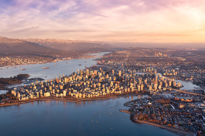 High angle view of river and buildings against sky during sunset