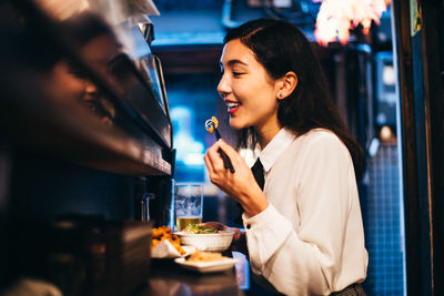 Young woman holding drink in restaurant