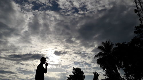 Silhouette man standing by trees against sky during sunset