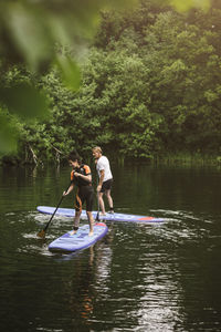 Senior man and woman learning paddleboarding in sea during sup course