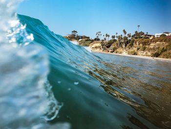 Surface level of beach against clear blue sky