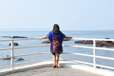 Rear view of woman looking at sea against clear sky