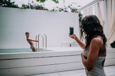 Rear view of man photographing woman using mobile phone