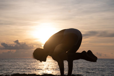 Silhouette man by sea against sky during sunset