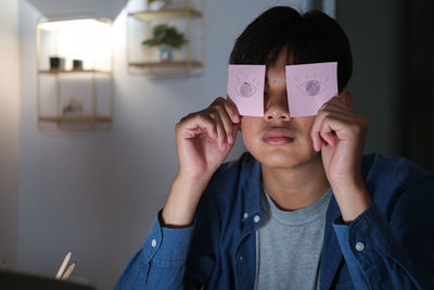 Portrait of teenage girl covering face at home