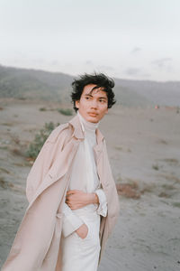 Young man looking away while standing on land against sky