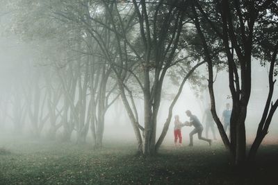 Full length of woman standing by trees in forest