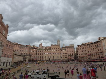 People at town square against cloudy sky