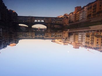 Arch bridge over river against buildings in city