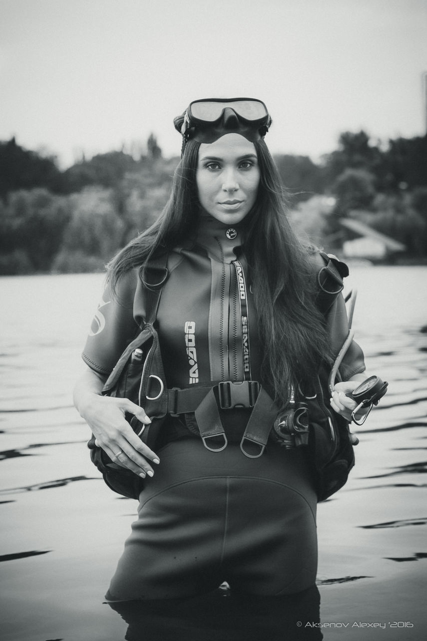 PORTRAIT OF BEAUTIFUL YOUNG WOMAN WEARING SUNGLASSES AGAINST LAKE