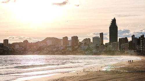 View of buildings at beach against sky during sunset