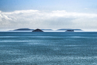 Scenic view of blue sea against cloudy sky