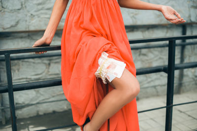 Low section of woman holding hands while standing by railing