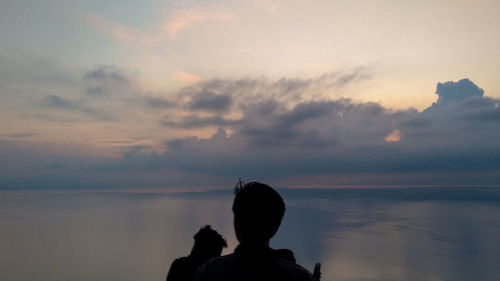 Rear view of silhouette man against sky during sunset
