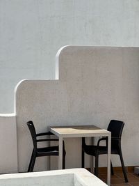 Empty chairs and table against wall