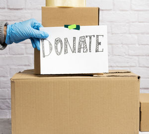 Stack of cardboard boxes and white sheet of paper with inscription donate on whi