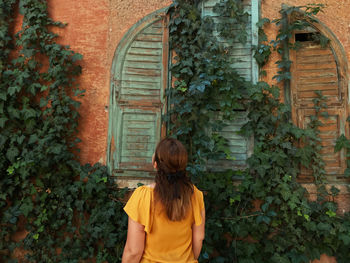 Rear view of woman standing against building