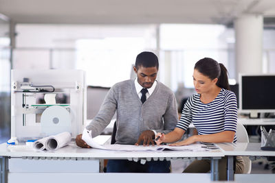 Architecture explaining blue print to colleague at office