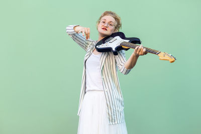 Portrait of smiling young woman standing against blue background